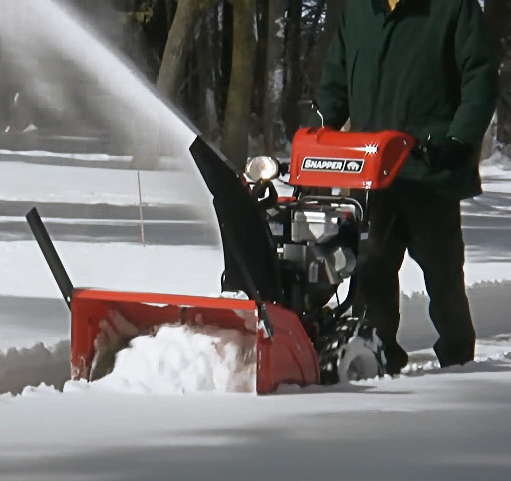 Man snowblowing with snapper snow blowing